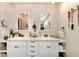 Bright bathroom featuring dual sinks, vanity with drawers, and an open shelf for storage at 7794 Louviers Blvd, Louviers, CO 80131