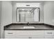 Bathroom vanity featuring dark countertops, white cabinets, a vessel sink and a rectangular mirror at 6842 Garland St, Arvada, CO 80004