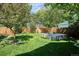 Green backyard featuring a well-maintained lawn, raised garden beds, a tree, and a wooden fence at 1109 Jersey St, Denver, CO 80220