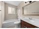 Traditional bathroom boasting a wood vanity, combined tub and shower, and neutral tile at 9196 W Maplewood Ave, Littleton, CO 80123