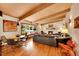 Open-concept living room with hardwood floors, beamed ceilings, and a brick fireplace at 4701 Homestead St, Bow Mar, CO 80123