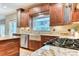 Close-up of kitchen with granite countertops, custom cabinets, stainless steel appliances, and a farmhouse style sink at 16458 W Ellsworth Dr, Golden, CO 80401
