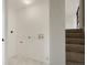 Hallway with laundry hookups adjacent to staircase and a tiled floor at 14544 March Dr, Denver, CO 80239