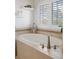 Bathroom featuring a tiled soaking tub with chrome fixtures and a large window with shutters at 4495 Rainbow Ln, Broomfield, CO 80020