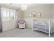 Bright Bedroom featuring a crib, armchair, chandelier, and window with sheer curtains at 4495 Rainbow Ln, Broomfield, CO 80020