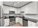 Well-equipped kitchen with stainless steel appliances, white cabinets, subway tile backsplash, and dark countertops at 6940 E Girard Ave # 210, Denver, CO 80224