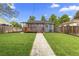 Fenced backyard with a lush lawn and a stone walkway that leads to a charming wooden deck at 1238 Rosemary St, Denver, CO 80220