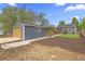 View of the garage and the home's fenced backyard with mature trees and manicured lawn at 1238 Rosemary St, Denver, CO 80220