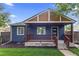 Charming blue home featuring a covered front porch with brown railings and a well-maintained lawn at 1238 Rosemary St, Denver, CO 80220