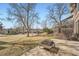 Backyard with mature trees and grass has a concrete patio with a fire pit at 1408 W Briarwood Ave, Littleton, CO 80120