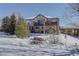 View of backyard with patios featuring hot tub, outdoor kitchen, and snowy seating areas at 10914 W Coco Pl, Littleton, CO 80127