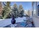 An outdoor sitting area with a fireplace and ornate metal chairs nestled among snow-covered evergreens at 10914 W Coco Pl, Littleton, CO 80127