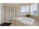 Inviting bathroom featuring tiled walls, a soaking tub, a glass shower, and plantation shutters for natural light at 10914 W Coco Pl, Littleton, CO 80127