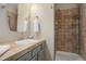 Tiled bathroom featuring a shower with shelving, oval mirror, and neutral color palette at 10914 W Coco Pl, Littleton, CO 80127