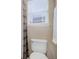 A close-up of a toilet with a window and a curtain above it at 10914 W Coco Pl, Littleton, CO 80127