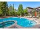 Community pool and hot tub with lounge chairs and tables surrounded by green trees at 50 Mountain Thunder Dr # 1402, Breckenridge, CO 80424