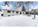 Backyard with snow-covered lawn, fire pit, seating area, and a white brick house with dark trim, offering a serene outdoor space at 12029 W Dakota Dr, Lakewood, CO 80228