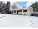 Charming ranch home with updated exterior, snowy landscape, and a black fence at 12029 W Dakota Dr, Lakewood, CO 80228