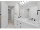 Neutral bathroom featuring double sinks, large mirror, white cabinets and modern fixtures at 7 Mockingbird Ln, Cherry Hills Village, CO 80113