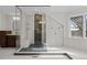 Bright bathroom featuring a seamless glass shower with tiled walls and pebble floor, plus modern fixtures and a built-in bench at 7 Mockingbird Ln, Cherry Hills Village, CO 80113