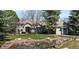 Stunning home exterior with lush lawn, mature trees, and serene pond with rock accents at 7 Mockingbird Ln, Cherry Hills Village, CO 80113