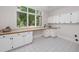 This bright laundry room features tile floors, counter space, and white cabinets at 7 Mockingbird Ln, Cherry Hills Village, CO 80113
