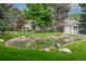 Backyard pond surrounded by lush green grass and mature trees, creating a serene and picturesque outdoor space at 7 Mockingbird Ln, Cherry Hills Village, CO 80113
