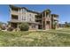 Multi-level condo building shows manicured lawn, brick accents, and upper level balconies at 12818 Ironstone Way # 101, Parker, CO 80134