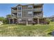 Three-story home exterior featuring covered patios, green lawn, landscaping, and unit number 12818 at 12818 Ironstone Way # 101, Parker, CO 80134