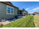 Side yard of home with well maintained grass and garden level entrance with a grill at 3375 New Haven Cir, Castle Rock, CO 80109