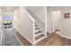 Hallway with wood floors, stairway, and views to the dining room and entry to a bathroom at 5805 Red Barn Ave, Mead, CO 80504