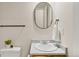 Cozy bathroom features oval mirror, vanity sink, and a white hand towel hanging on a rack at 6602 S Vance St, Littleton, CO 80123