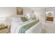 A well-lit bedroom showcasing a comfortable bed with throw blanket, side table, and bright ensuite bathroom at 6602 S Vance St, Littleton, CO 80123