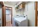 Bright laundry room featuring a modern washer and dryer, overhead shelving, and adjacent half bathroom at 6323 W 85Th Ave, Arvada, CO 80003