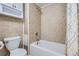 Cozy bathroom featuring beige tile walls, a white toilet, and a bathtub with shower at 9995 E Harvard Ave # 246, Denver, CO 80231