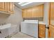 Functional laundry room with washer, dryer, utility sink, cabinet storage, and countertop space at 8136 S Glencoe Ct, Centennial, CO 80122