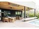 Elegant covered patio adjacent to the pool featuring an outdoor dining area, seating, and modern fire feature at 140 S Glencoe St, Denver, CO 80246