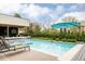 Sparkling swimming pool surrounded by lounge chairs, a lush garden, umbrella, and an outdoor kitchen at 140 S Glencoe St, Denver, CO 80246