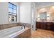 Bright bathroom featuring a soaking tub, large window, and stylish tile accents at 7821 Inverness Blvd, Englewood, CO 80112