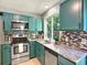 Stylish kitchen featuring granite countertops, stainless steel appliances, and teal cabinetry at 453 Arden Cir, Highlands Ranch, CO 80126