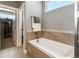 Spa-like bathroom featuring a soaking tub, large mirror, neutral tile, and walk in closet at 31353 E 163Rd Ave, Hudson, CO 80642