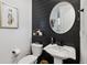 Chic powder room with a sleek pedestal sink, modern fixtures, and stylish decor on a striking black accent wall at 8403 Rush Creek Ave, Littleton, CO 80125