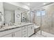 Well-lit bathroom featuring a double vanity with granite countertops and a modern tiled shower with a built-in seat at 8403 Rush Creek Ave, Littleton, CO 80125