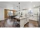 Bright open-concept kitchen featuring white cabinets, granite countertops, stainless steel appliances, and hardwood floors at 8403 Rush Creek Ave, Littleton, CO 80125
