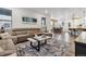 An open-concept living room featuring a plush sectional couch, a patterned rug, and views into the dining and kitchen areas at 8403 Rush Creek Ave, Littleton, CO 80125