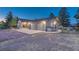 A well-lit home exterior featuring a three-car garage and ample parking on a gravel driveway at 345 Scrub Oak Way, Monument, CO 80132