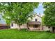 Exterior view of the house from the backyard, featuring a lawn, playground, large tree, and covered patio at 9502 W Hialeah Pl, Littleton, CO 80123