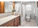 Bright bathroom featuring a single vanity with wooden cabinets, tile floors, and a shower/tub with a window at 9502 W Hialeah Pl, Littleton, CO 80123