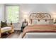Cozy bedroom featuring a wicker headboard, wood floors, and natural light from a large window at 9502 W Hialeah Pl, Littleton, CO 80123