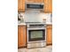 Close up view of a stainless steel oven beneath a matching microwave and wood cabinetry at 9502 W Hialeah Pl, Littleton, CO 80123